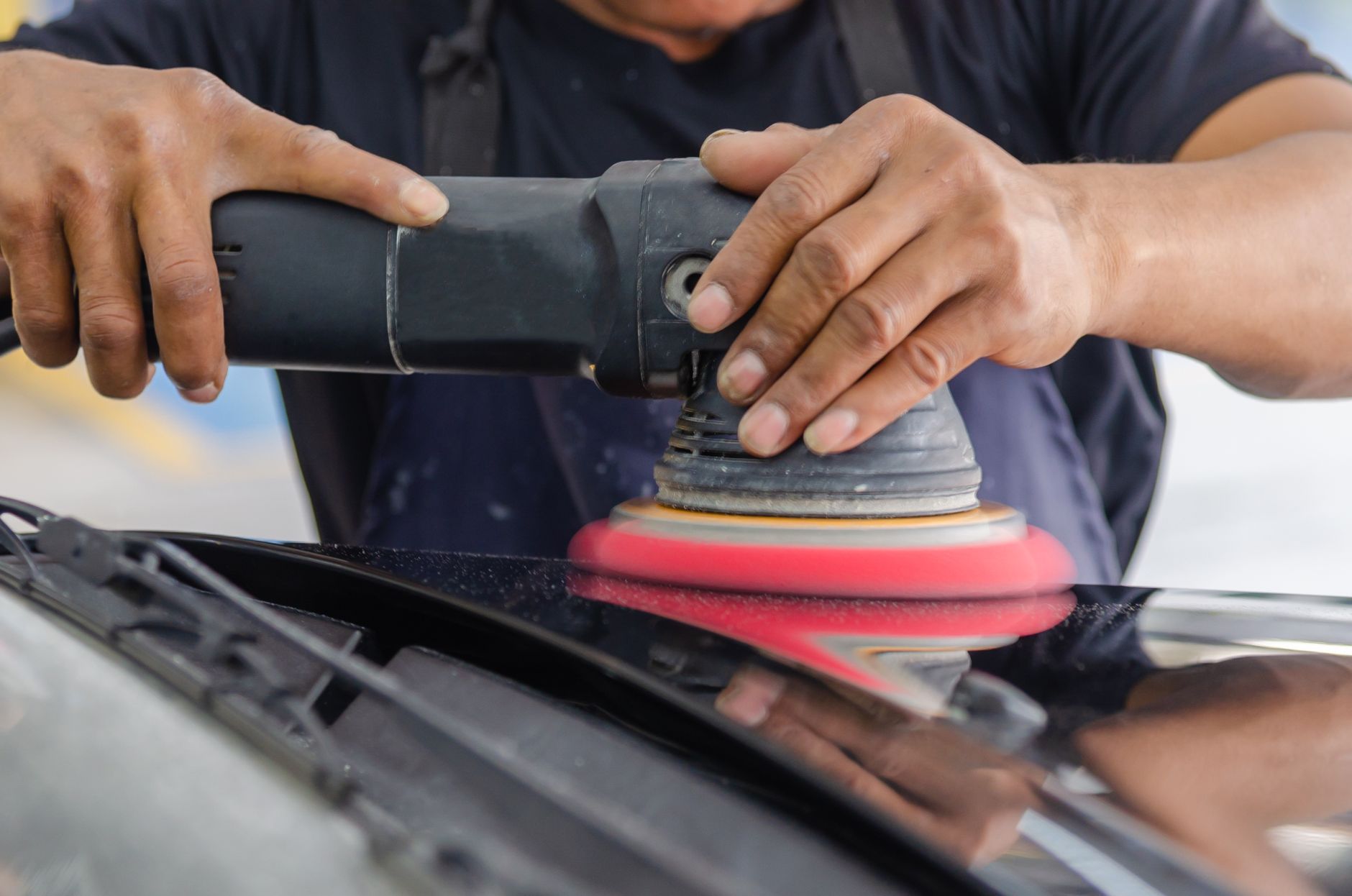 Juruteknik menggilap badan kereta dengan mesin buffer